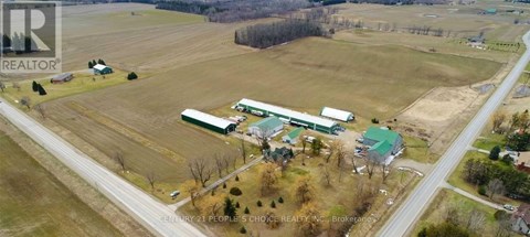 A farm with a green barn and a red roof is surrounded by a road.