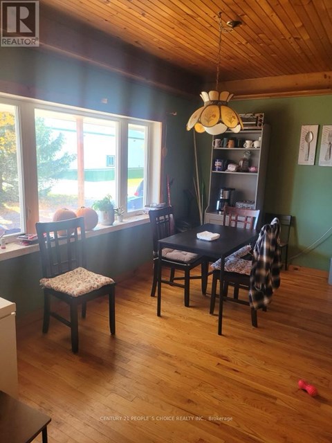 A room with wooden floors and a window with a view of trees and a building outside.