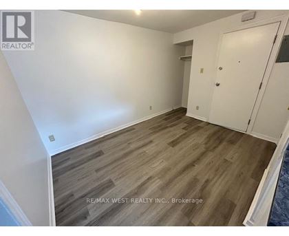 A room with wooden flooring and white walls, with a door on the right side.