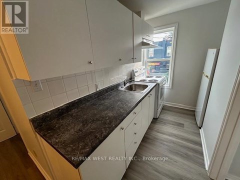 A kitchen with white cabinets and a black countertop.
