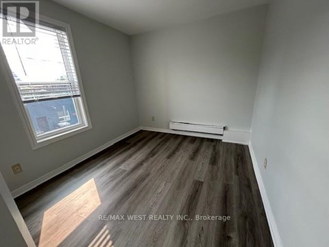 A room with a window and a wooden floor.