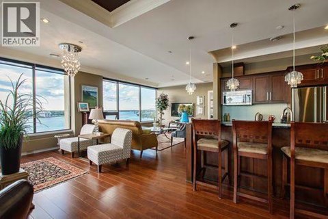 A living room with a large window and a dining area with chairs.