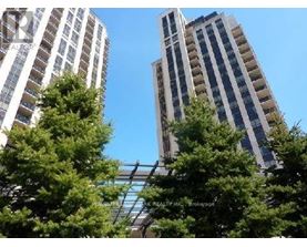Two tall buildings are seen behind some trees.
