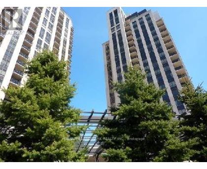 Two tall buildings are seen behind some trees.
