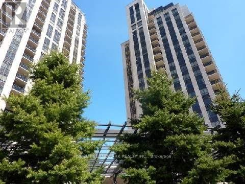 Two tall buildings are seen behind some trees.