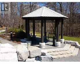 A gazebo with a metal roof is surrounded by stone pillars and a stone wall.