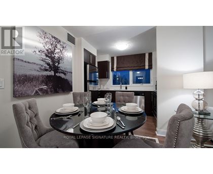 A dining room with a table set for two and a large landscape picture on the wall.