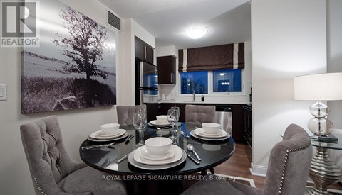 A dining room with a table set for two and a large landscape picture on the wall.