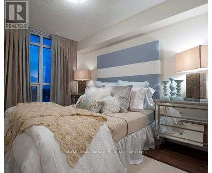 A bedroom with a bed, nightstand, and lamp.