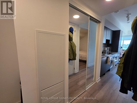 A bedroom with a mirrored wardrobe and a bed in the background.