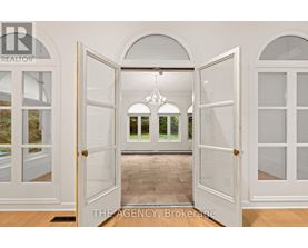 A white door is open to a hallway with a chandelier.