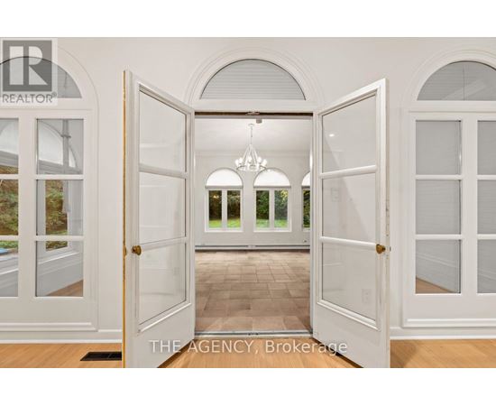 A white door is open to a hallway with a chandelier.
