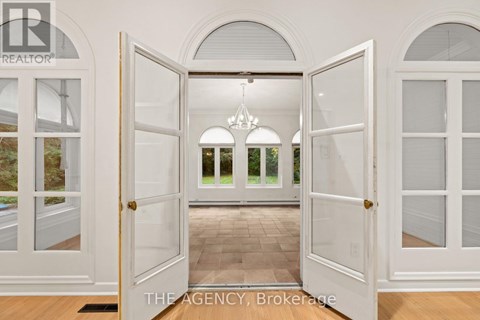 A white door is open to a hallway with a chandelier.