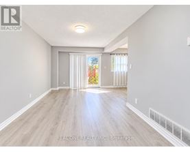 A spacious room with light wood flooring and white walls, with a sliding glass door leading to a garden.