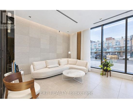 A living room with a white couch and a wooden chair.