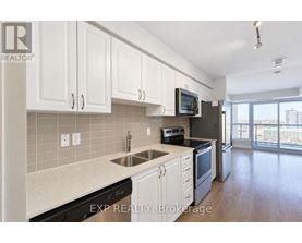 A kitchen with white cabinets and a black fridge.