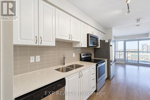 A kitchen with white cabinets and a black fridge.