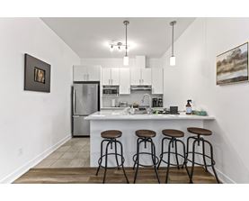 A kitchen with white cabinets and a white island with three stools.