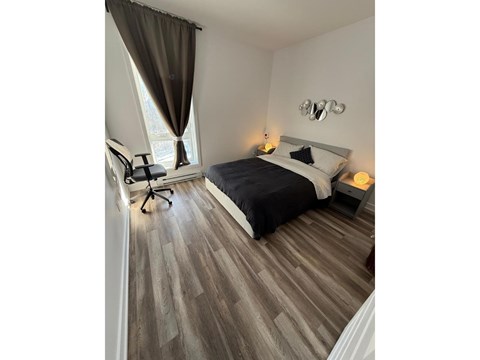 A bedroom with a bed, chair, and window.