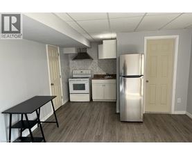 A kitchen with a stainless steel refrigerator, a black table, and white cabinets.