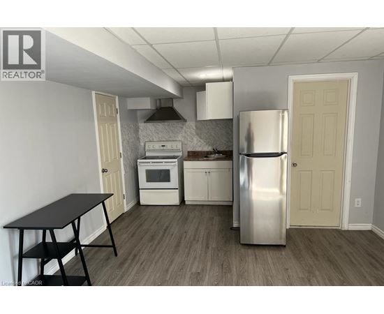 A kitchen with a stainless steel refrigerator, a black table, and white cabinets.
