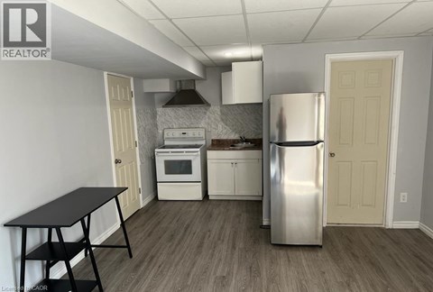 A kitchen with a stainless steel refrigerator, a black table, and white cabinets.