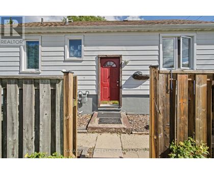A small house with a red door is surrounded by a wooden fence.