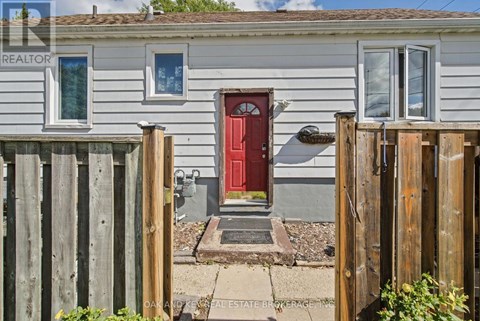 A small house with a red door is surrounded by a wooden fence.