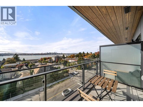 A balcony with a chair and a view of a street and buildings.