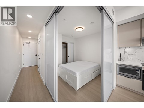 A bedroom with a bed, a microwave, and a fridge.