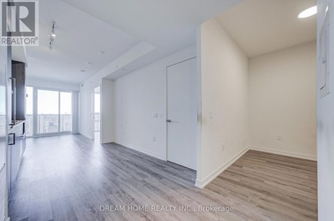 A spacious room with wooden flooring and white walls.