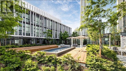 A modern building with a pool in the foreground and a tree in the background.