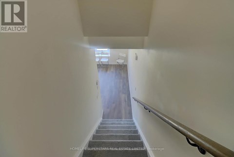 A stairway with a wooden handrail leads to a door at the end.