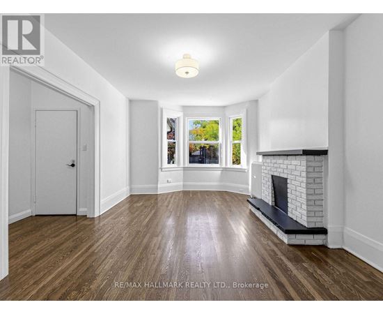 A spacious room with a fireplace and a view of trees through the window.