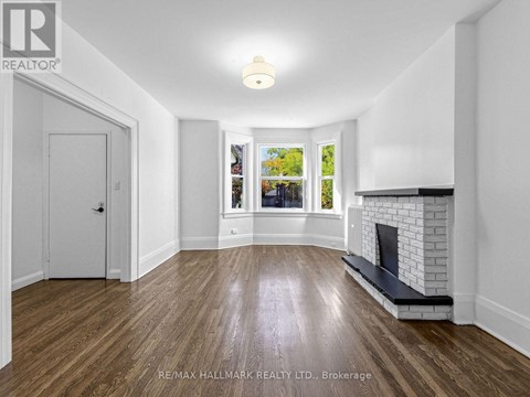 A spacious room with a fireplace and a view of trees through the window.