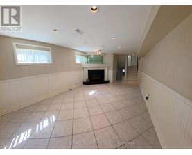 A spacious room with a fireplace and a staircase.