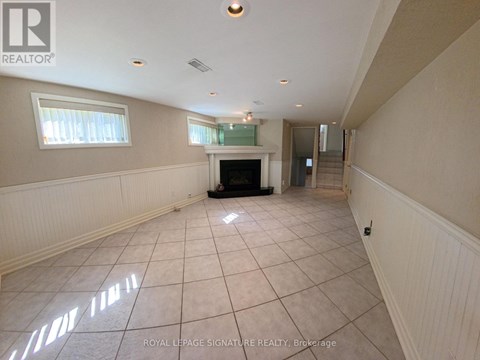A spacious room with a fireplace and a staircase.