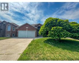 A house with a large driveway and a garage door is for sale.