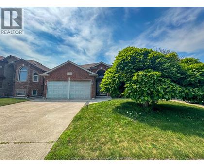 A house with a large driveway and a garage door is for sale.