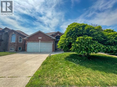 A house with a large driveway and a garage door is for sale.