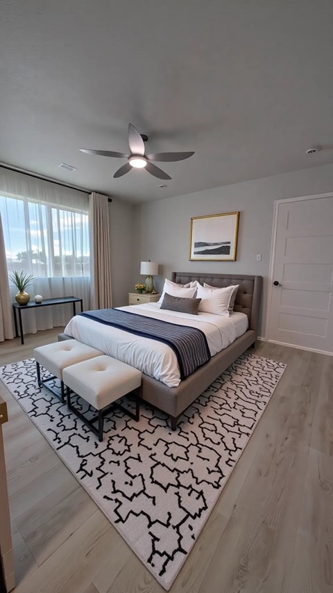 A bedroom with a large bed and a ceiling fan.