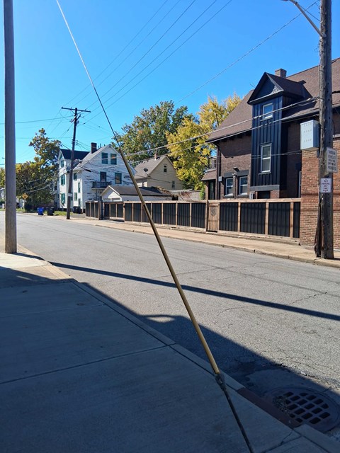 A street with a sidewalk and a building with a black awning.