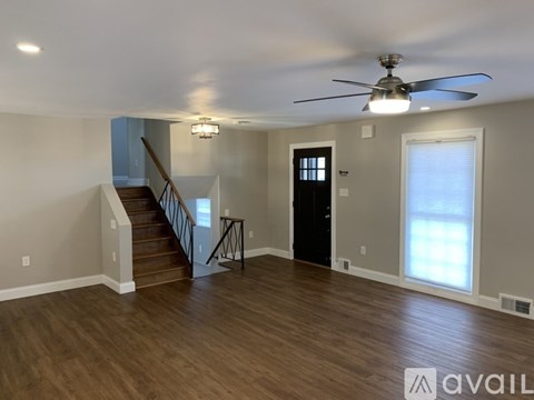 A spacious room with a staircase and a ceiling fan.