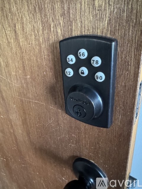 A black keypad with numbers 12, 34, 56, 78, and 90 is mounted on a wooden door.