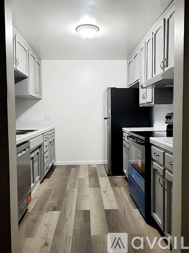A kitchen with a black refrigerator and wooden floors.
