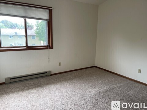 A room with a window and a carpeted floor.