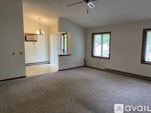 A spacious room with a ceiling fan and two windows.
