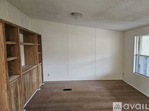A room with wooden floors and a white wall with a window.