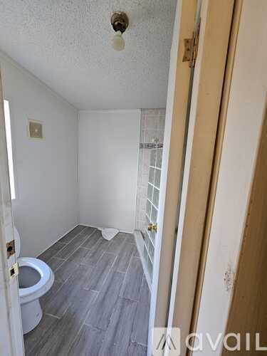 A bathroom with a toilet and a wooden floor.