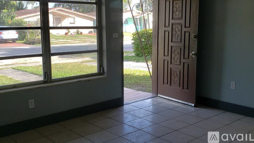 A room with a tiled floor, a door and a window overlooking a street.